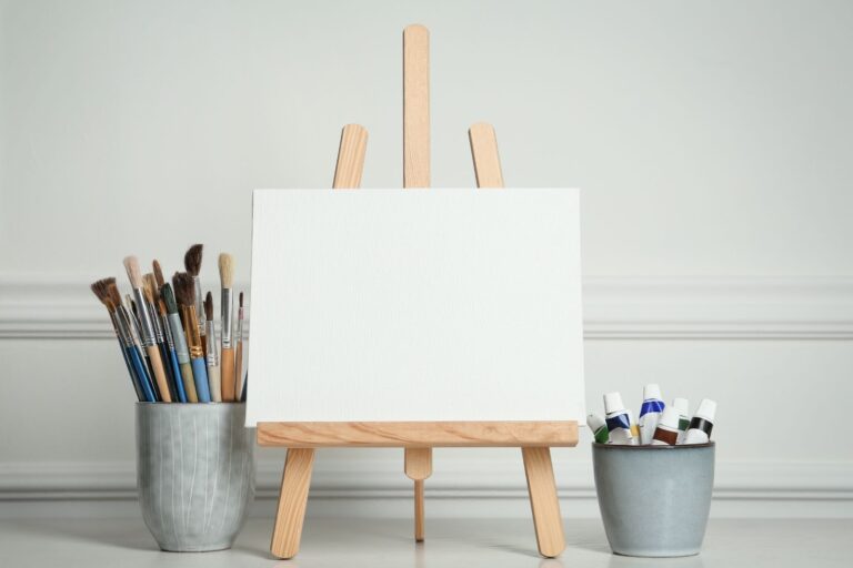A small wooden easel with a blank canvas and brushes in cups